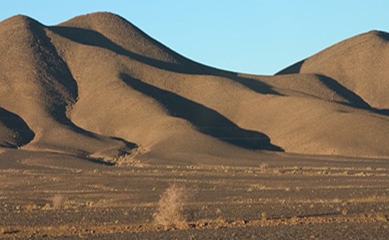 гористая местность сменяется каменистой равниной, за которой начнется классическая, песчаная пустыня с барханами. Силуэты гор уже сглажены – издали их можно принять за огромные дюны.